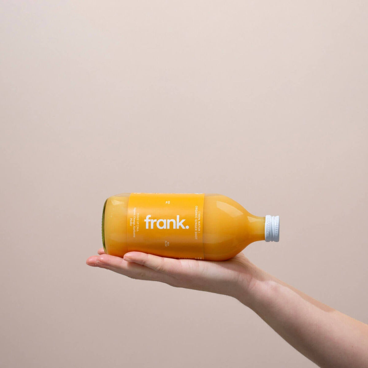 Hand hält die frank Ingwer Shot Wake Up Call Flasche mit 500 Millilitern